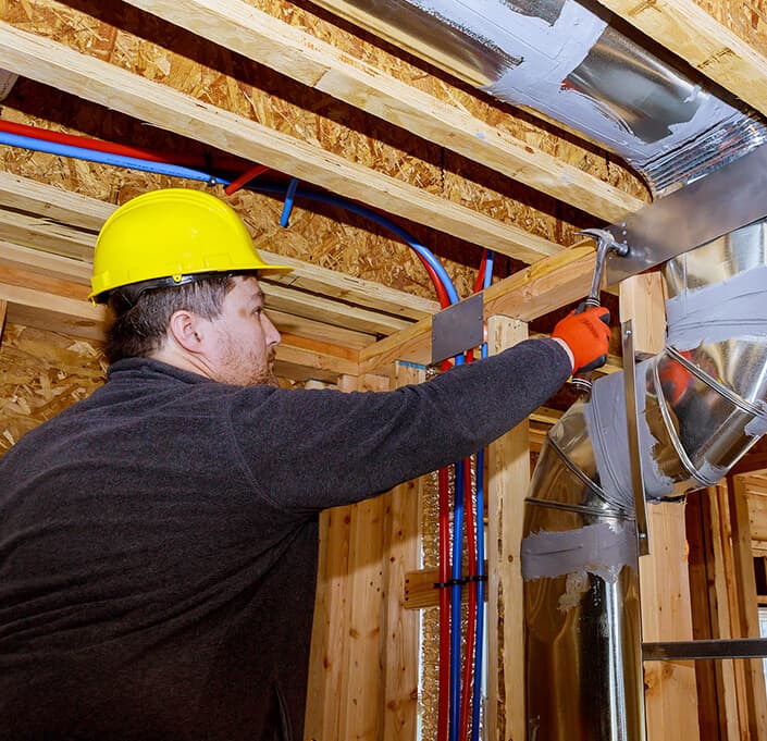 Technician cleaning and repairing an air duct